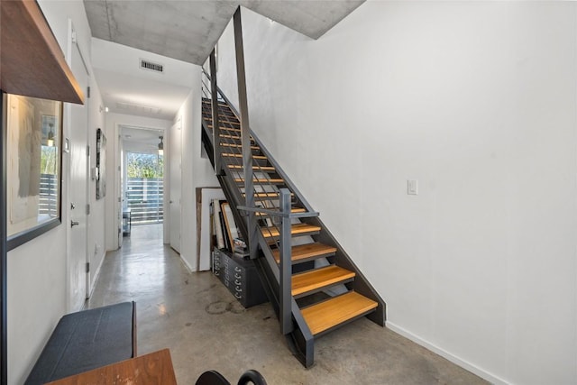 stairway with visible vents, baseboards, and concrete floors