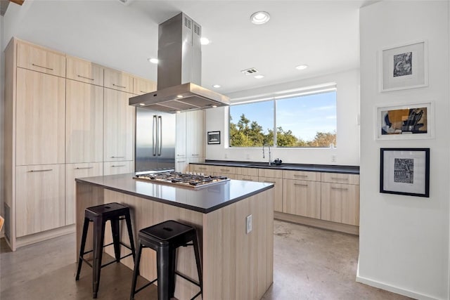 kitchen with appliances with stainless steel finishes, light brown cabinets, island exhaust hood, and finished concrete flooring