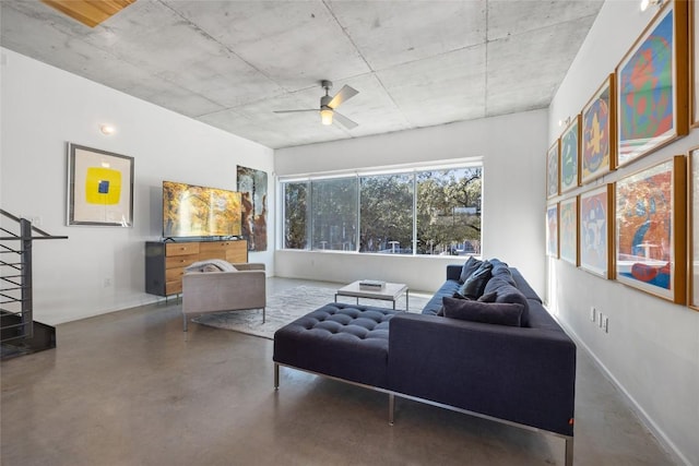 living area featuring baseboards, concrete flooring, and ceiling fan