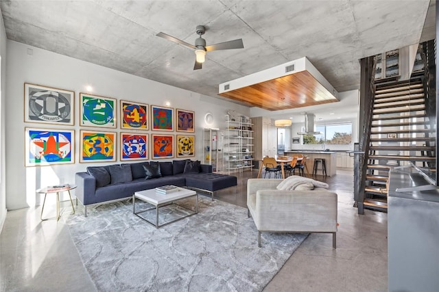 living area featuring stairway, a ceiling fan, visible vents, and finished concrete floors