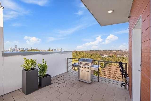 view of patio featuring a city view, a grill, and a balcony