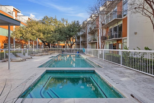 view of swimming pool with fence and a hot tub