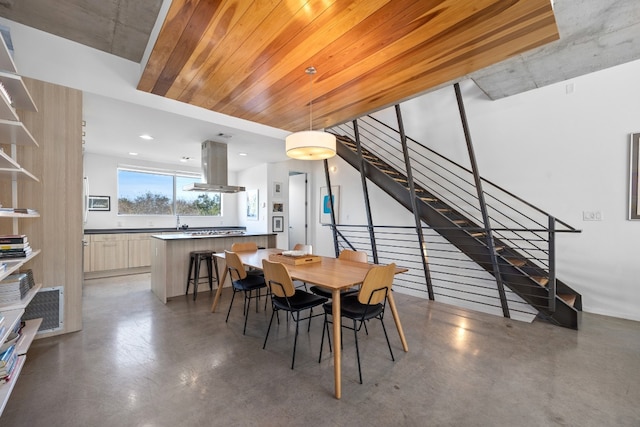 dining room featuring stairway and finished concrete flooring