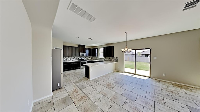 kitchen featuring visible vents, a peninsula, light countertops, appliances with stainless steel finishes, and backsplash