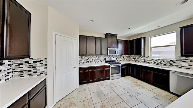 kitchen featuring a sink, backsplash, dark brown cabinetry, appliances with stainless steel finishes, and light countertops