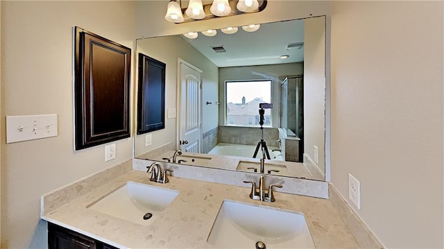 bathroom with double vanity, a garden tub, visible vents, and a sink