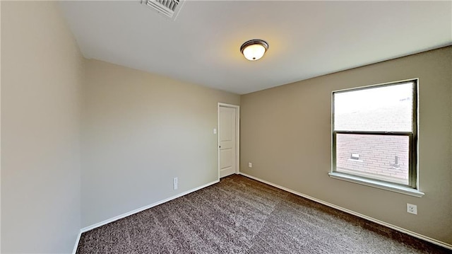 empty room featuring visible vents, baseboards, and dark colored carpet