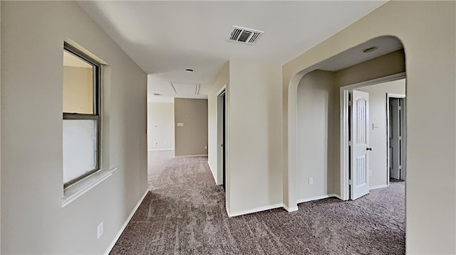 hall featuring visible vents, baseboards, attic access, and carpet flooring