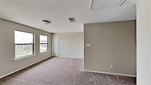 spare room featuring attic access, carpet flooring, visible vents, and baseboards