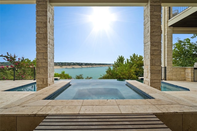 view of swimming pool featuring an in ground hot tub and a water view