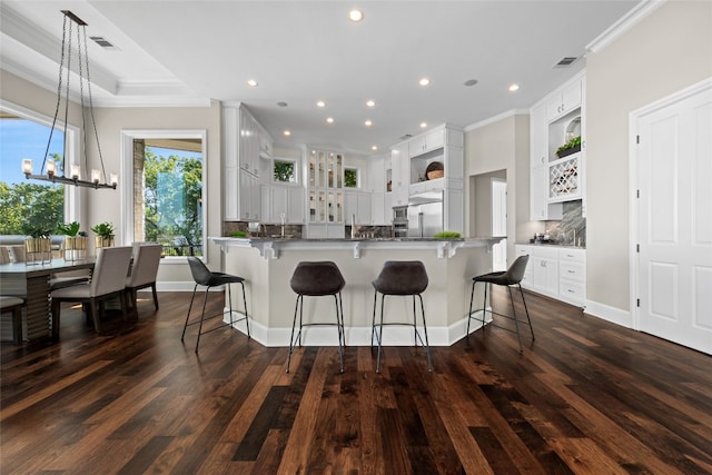 711 Cutlass, Lakeway, TX 78734 - kitchen with open shelves, a breakfast bar area, ornamental molding, dark wood-style flooring, and white cabinetry