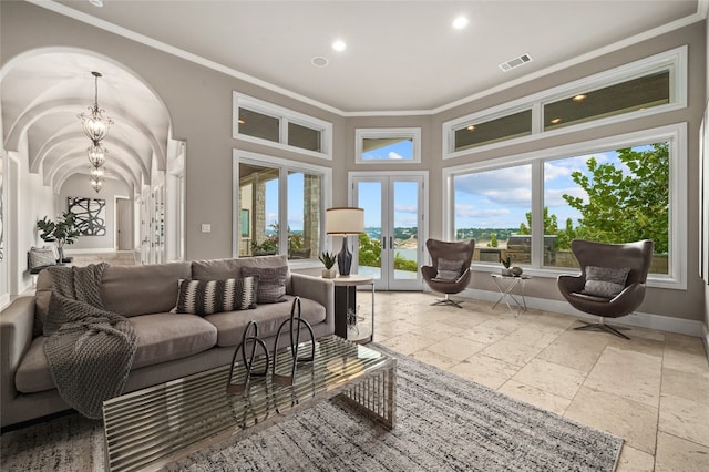 living area with stone tile flooring, french doors, crown molding, baseboards, and a chandelier