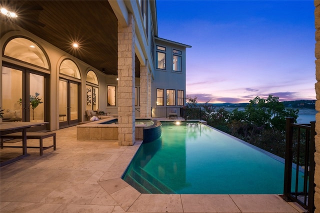 711 Cutlass, Lakeway, TX 78734 - pool at dusk featuring a patio and a pool with connected hot tub