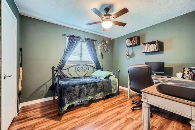 bedroom with light wood finished floors, ceiling fan, a textured ceiling, and baseboards