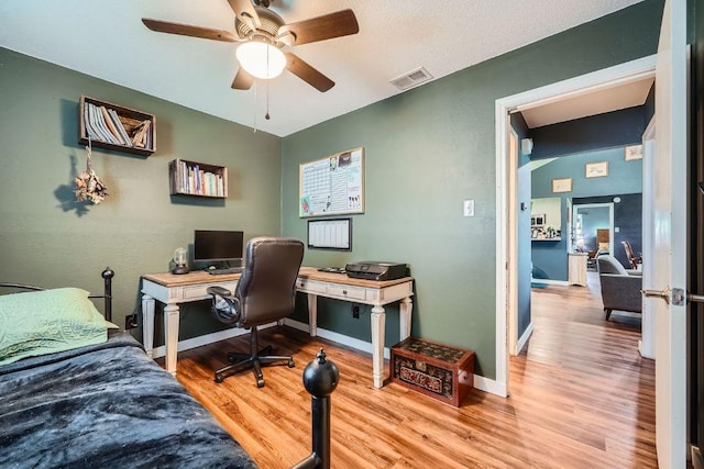 bedroom with ceiling fan, visible vents, baseboards, and wood finished floors