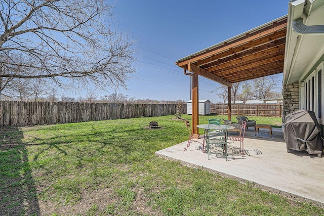 view of yard with a fenced backyard, an outdoor structure, a storage unit, a fire pit, and a patio area