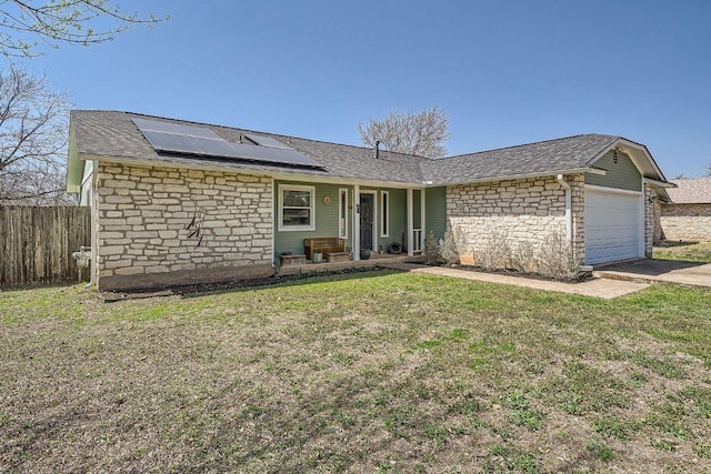 ranch-style house with a front yard, fence, solar panels, an attached garage, and stone siding