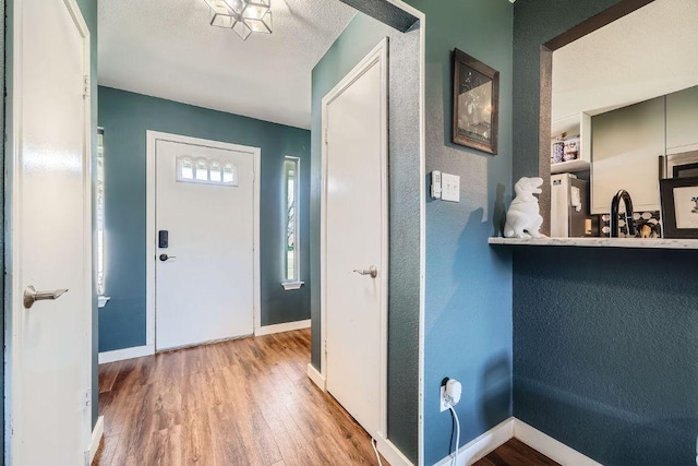 entrance foyer featuring wood finished floors, baseboards, and a textured ceiling