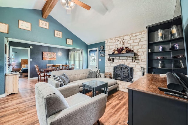 living room featuring wood finished floors, high vaulted ceiling, ceiling fan, a stone fireplace, and beamed ceiling