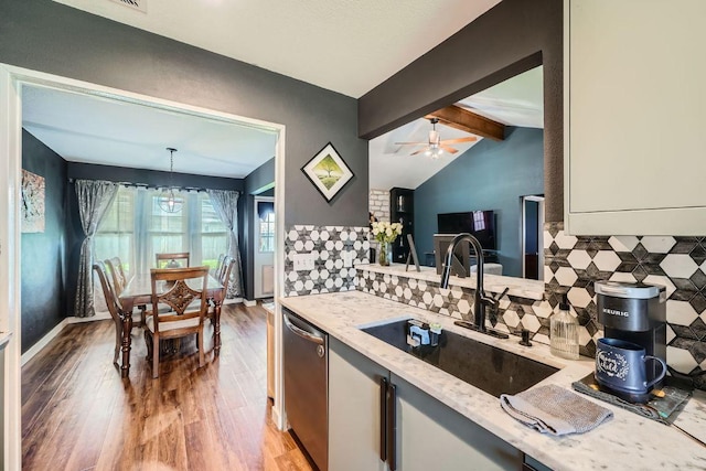 kitchen with a sink, light stone counters, stainless steel dishwasher, wood finished floors, and vaulted ceiling with beams