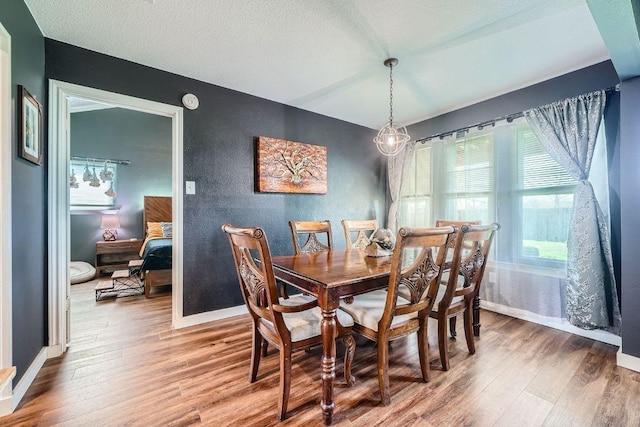 dining area with baseboards, a textured ceiling, and wood finished floors