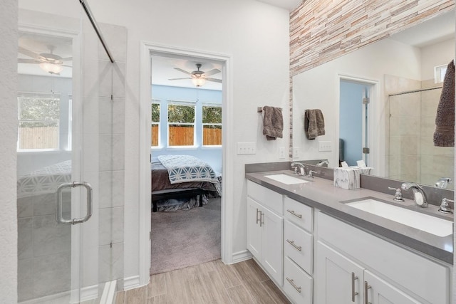 ensuite bathroom featuring a stall shower, a ceiling fan, and a sink