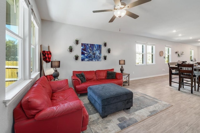 living room featuring ceiling fan, baseboards, and wood finished floors