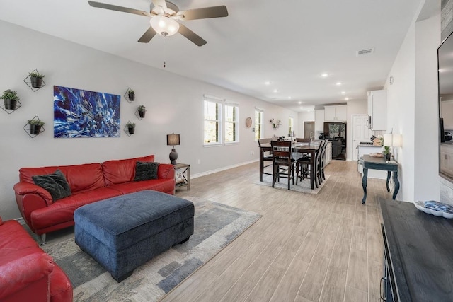 living area with light wood-type flooring, visible vents, a ceiling fan, recessed lighting, and baseboards