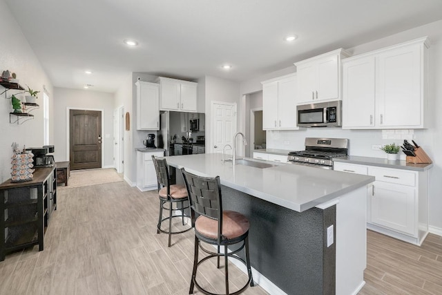 kitchen featuring a sink, appliances with stainless steel finishes, a kitchen breakfast bar, light wood-type flooring, and backsplash