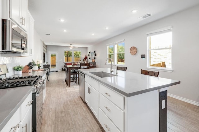 kitchen with visible vents, a sink, tasteful backsplash, appliances with stainless steel finishes, and light wood finished floors