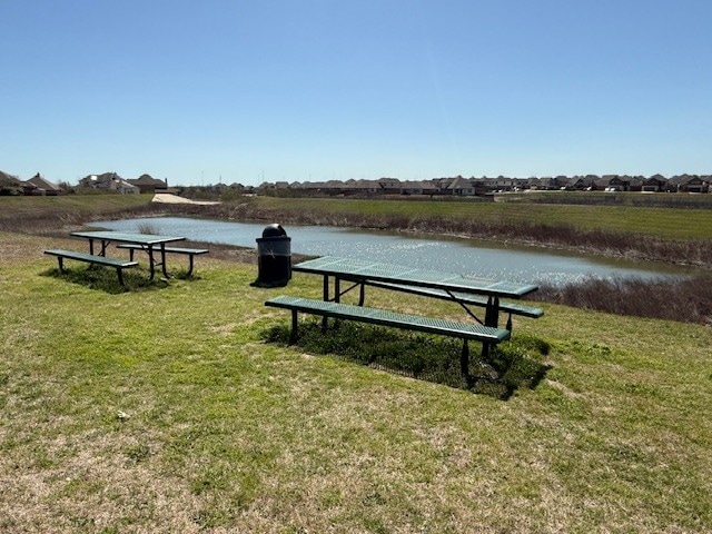 view of property's community featuring a lawn and a water view