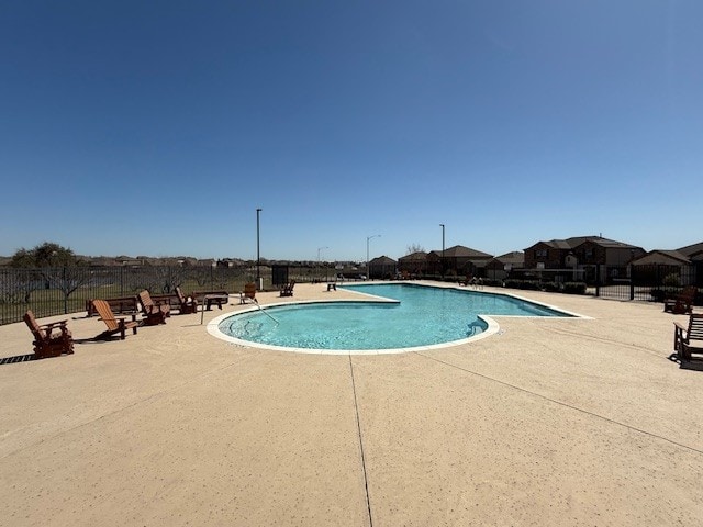 pool with a patio area and fence