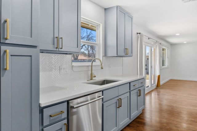 kitchen with backsplash, dishwasher, light countertops, gray cabinets, and a sink