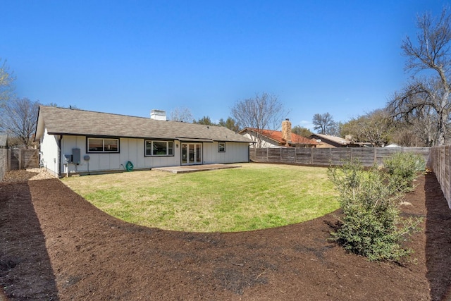 rear view of property with a lawn, a patio, a fenced backyard, board and batten siding, and a chimney