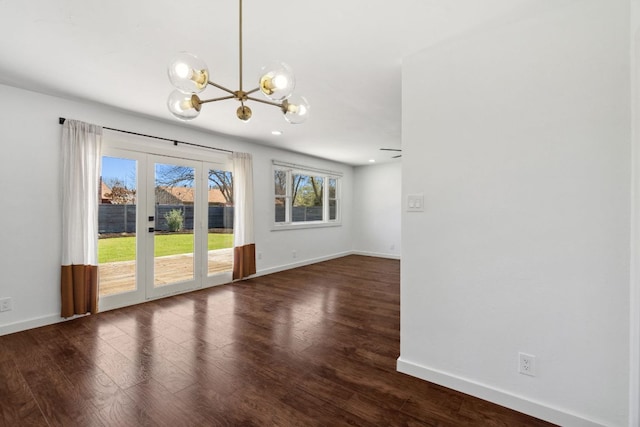 unfurnished room with baseboards, a notable chandelier, and dark wood finished floors