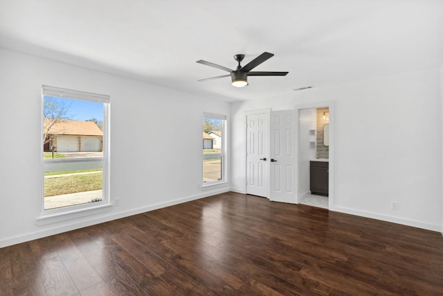 unfurnished bedroom featuring baseboards, multiple windows, and wood finished floors