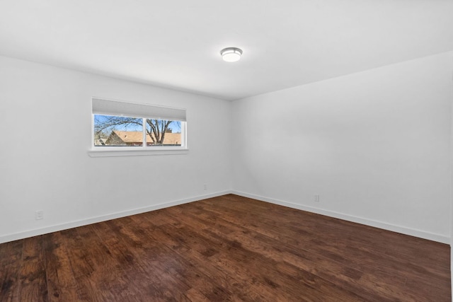 spare room featuring baseboards and dark wood-style flooring