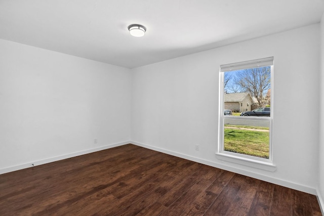 unfurnished room featuring baseboards and dark wood-type flooring