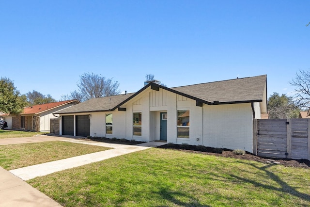 view of front facade featuring board and batten siding, fence, a front yard, driveway, and an attached garage