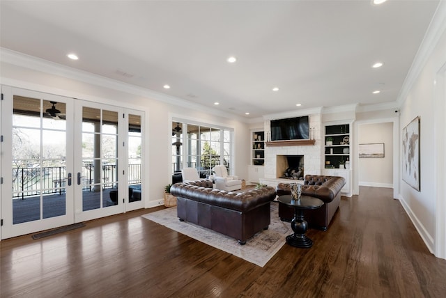 living area with a stone fireplace, crown molding, dark wood-style floors, and baseboards