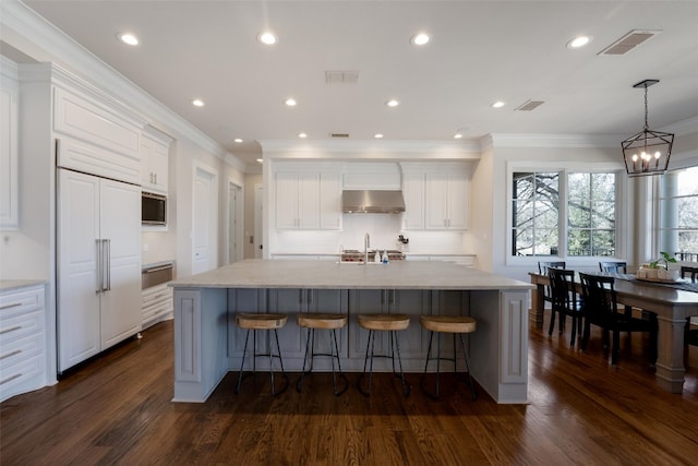 kitchen with under cabinet range hood, visible vents, built in appliances, and white cabinets