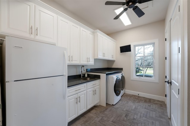 laundry area with independent washer and dryer, a ceiling fan, a sink, cabinet space, and baseboards