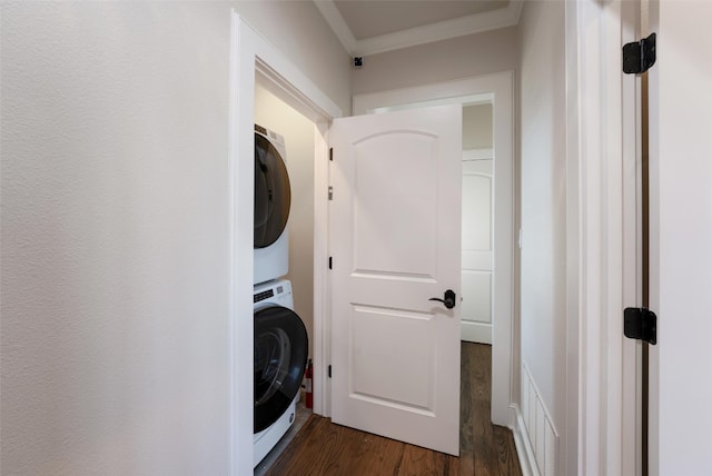 clothes washing area featuring visible vents, crown molding, laundry area, stacked washing maching and dryer, and dark wood-style floors