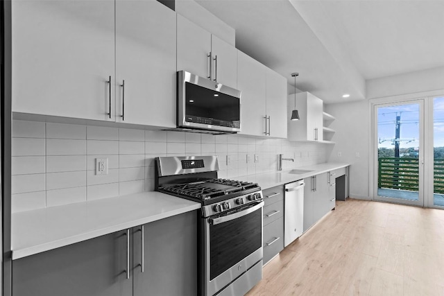 kitchen featuring light wood-style flooring, appliances with stainless steel finishes, light countertops, and open shelves