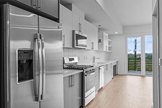 kitchen with light wood-type flooring, a sink, backsplash, stainless steel appliances, and light countertops