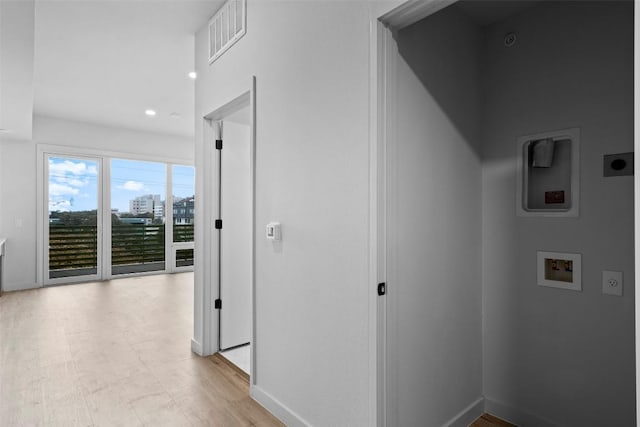 hallway with light wood-style flooring, baseboards, and visible vents