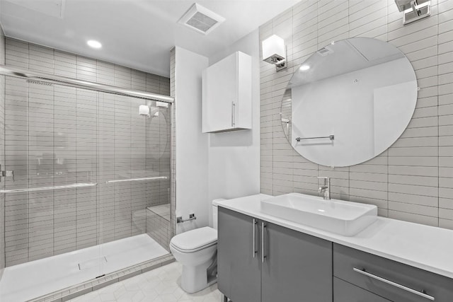 bathroom featuring visible vents, toilet, tile walls, a shower stall, and vanity