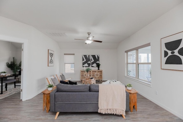 living area with visible vents, baseboards, a ceiling fan, and wood finished floors