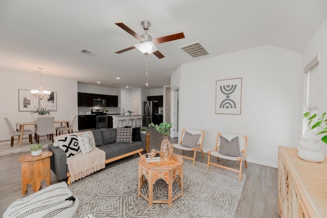 living room with visible vents, ceiling fan with notable chandelier, and light wood-type flooring