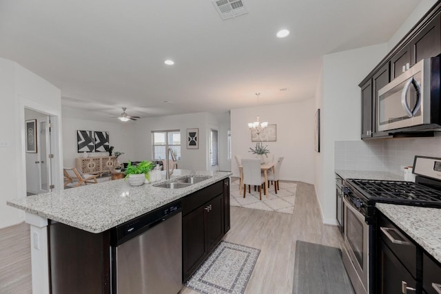 kitchen with light wood finished floors, visible vents, backsplash, stainless steel appliances, and a sink